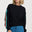 Woman wearing a black sweater with colorful sleeves against a white background