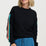 Woman wearing a black sweater with colorful sleeves against a white background