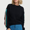 Woman wearing a black sweater with colorful sleeves against a white background
