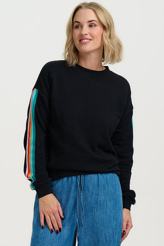 Woman wearing a black sweater with colorful sleeves against a white background