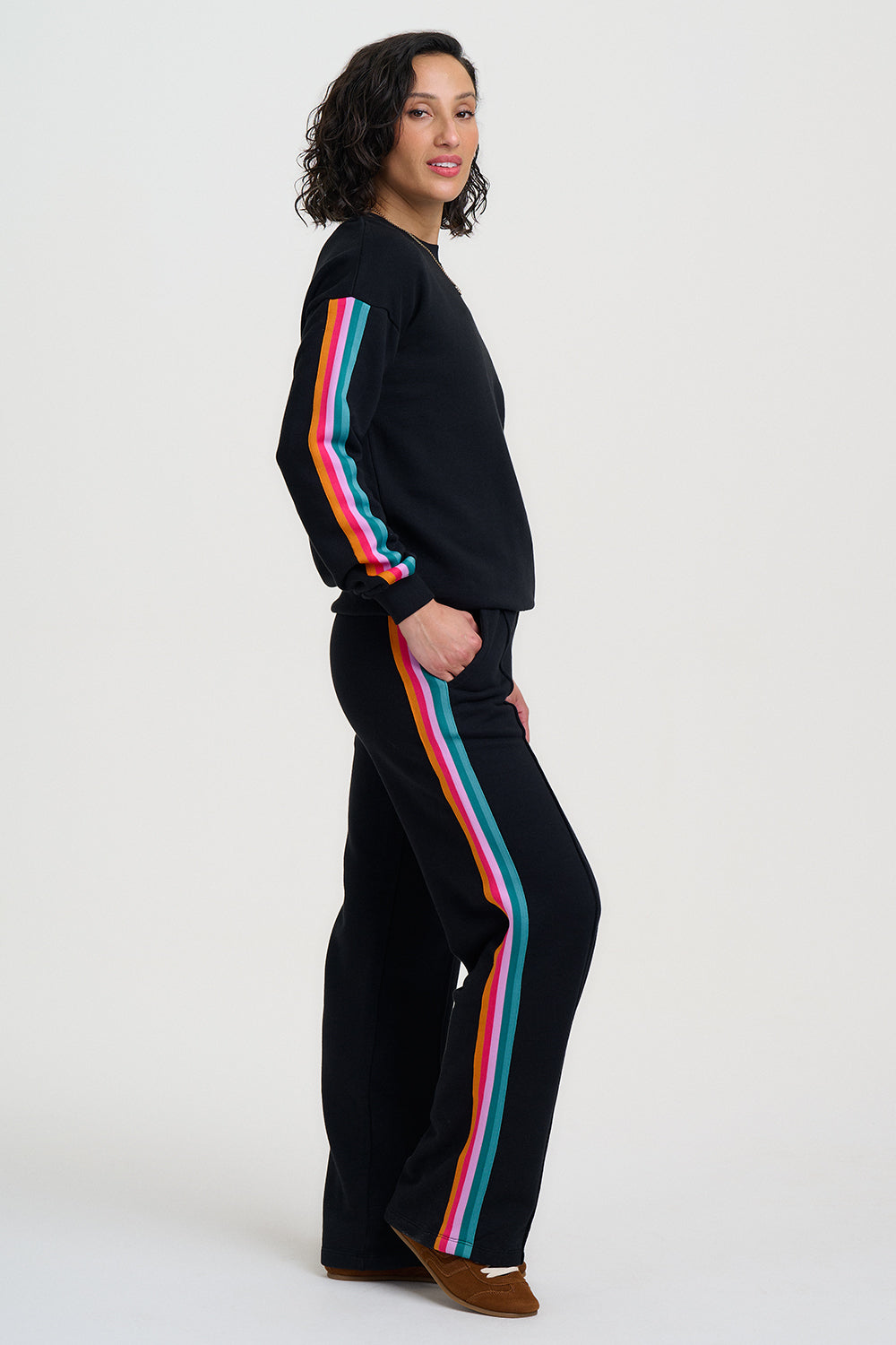 Person wearing a black tracksuit with colorful stripes on a white background