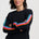 Woman wearing a black sweater with colorful stripes on a white background