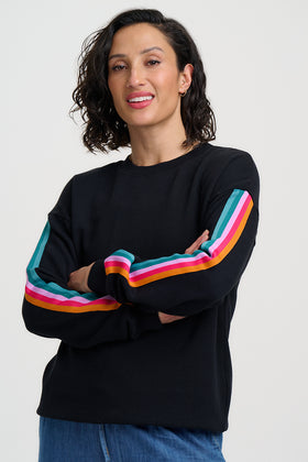 Woman wearing a black sweater with colorful stripes on a white background