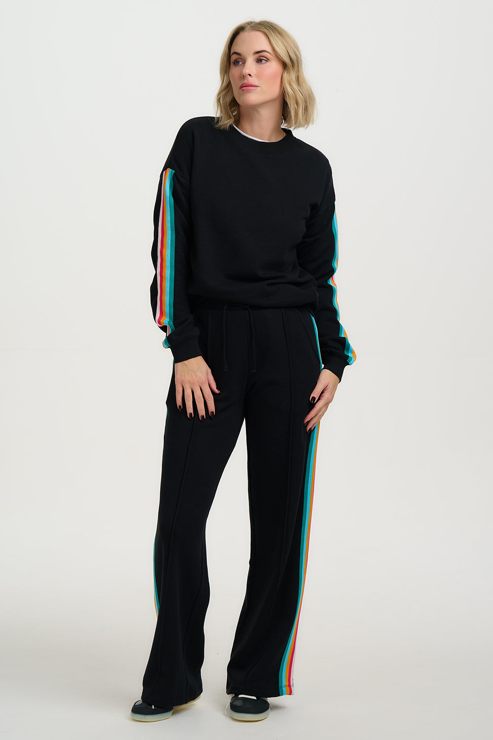 Woman wearing a black outfit with colorful stripes on a white background