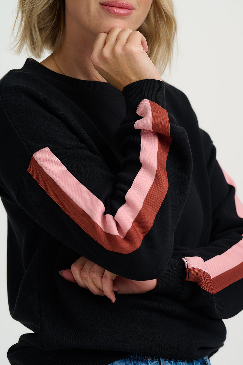 Black hoodie with pink and red stripes on sleeves against a neutral background