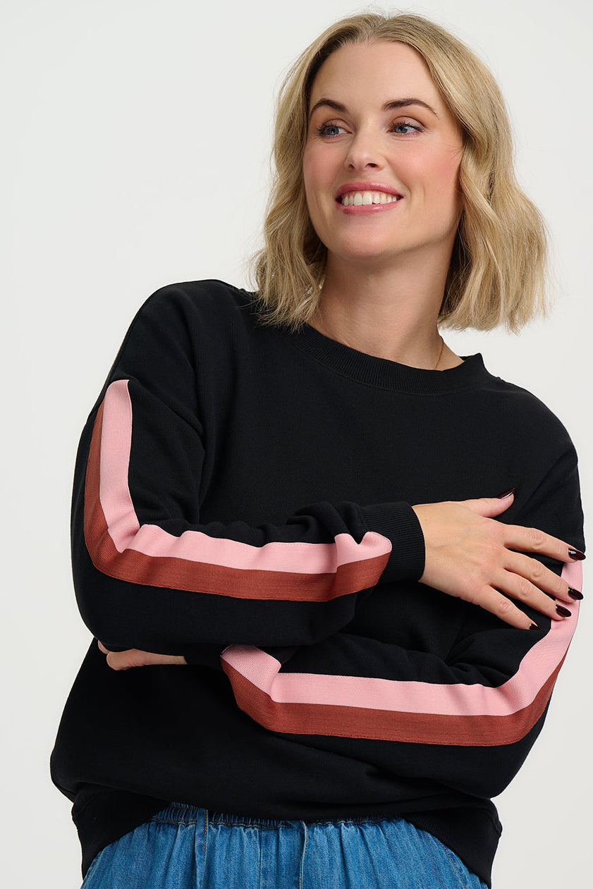 Woman wearing a black sweater with colorful sleeves against a white background