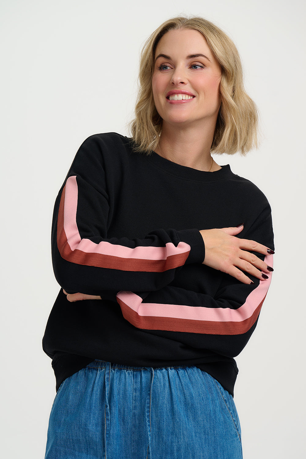 Woman wearing a black sweater with colorful sleeves against a white background