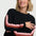 Woman wearing a black sweater with colorful sleeves against a white background