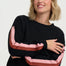 Woman wearing a black sweater with colorful sleeves against a white background