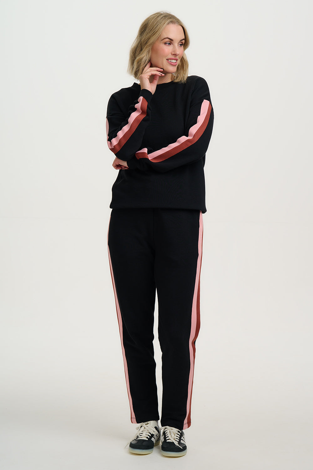 Woman wearing a black tracksuit with pink stripes on a white background