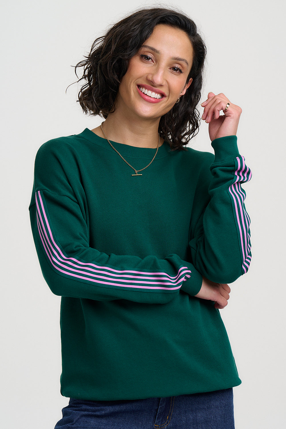 Woman wearing a green sweatshirt with pink stripes on a white background