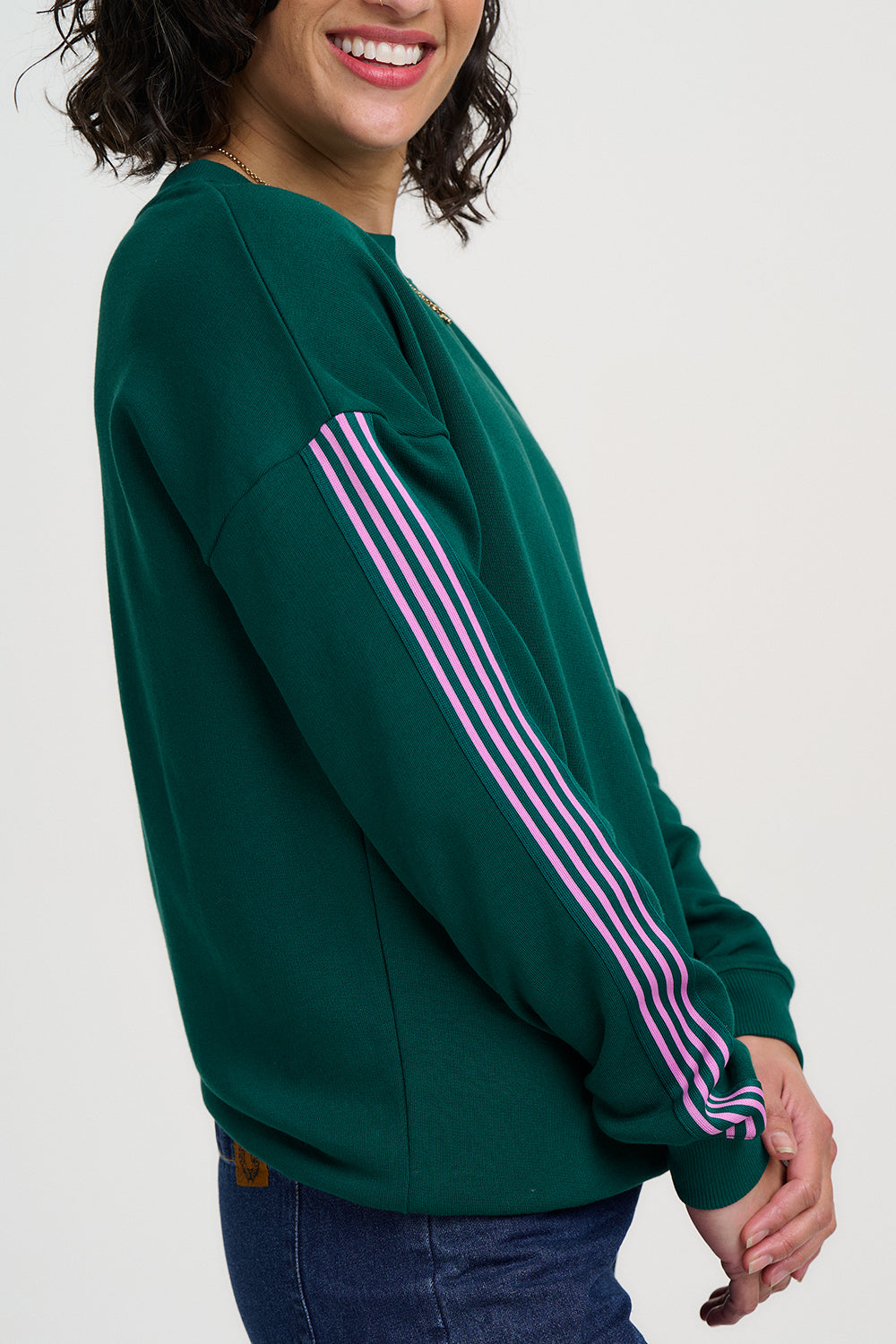 Green sweatshirt with pink stripes worn by a person on a white background