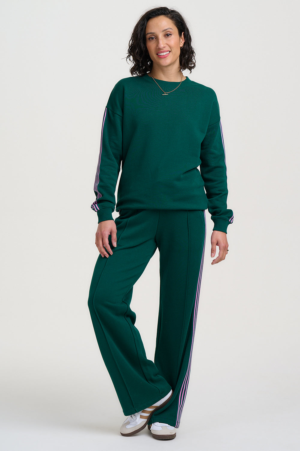 Woman wearing a green tracksuit with white stripes on a white background