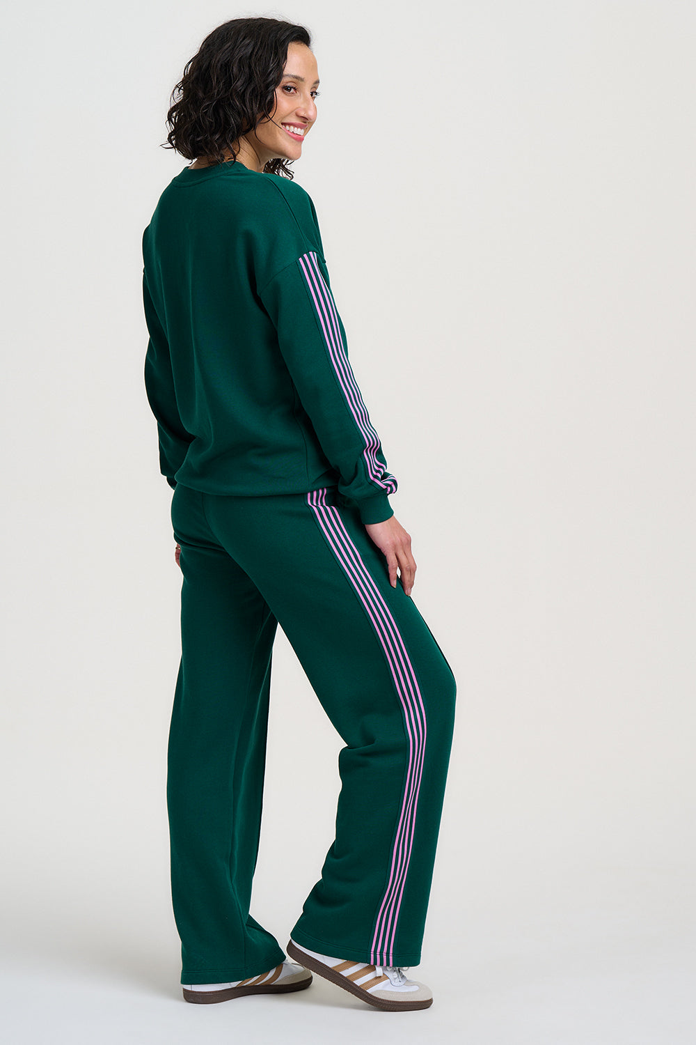 Person wearing a green tracksuit with white stripes on a white background