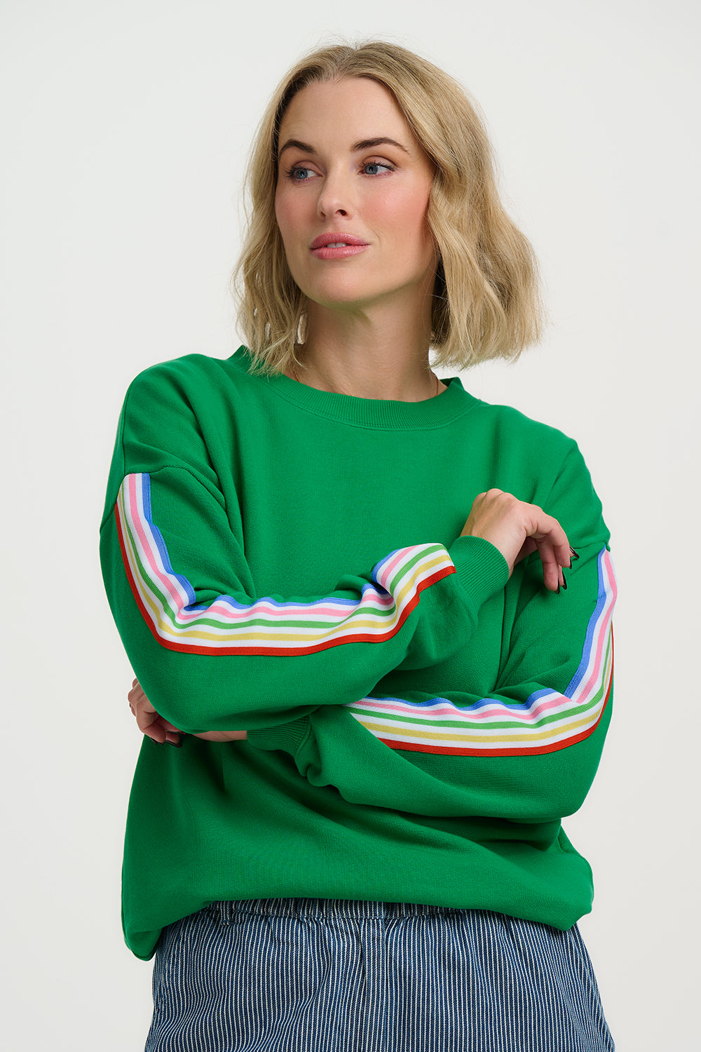 Woman wearing a green sweater with colorful stripes on a white background