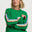 Woman wearing a green sweater with colorful stripes on a white background