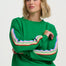 Woman wearing a green sweater with colorful stripes on a white background