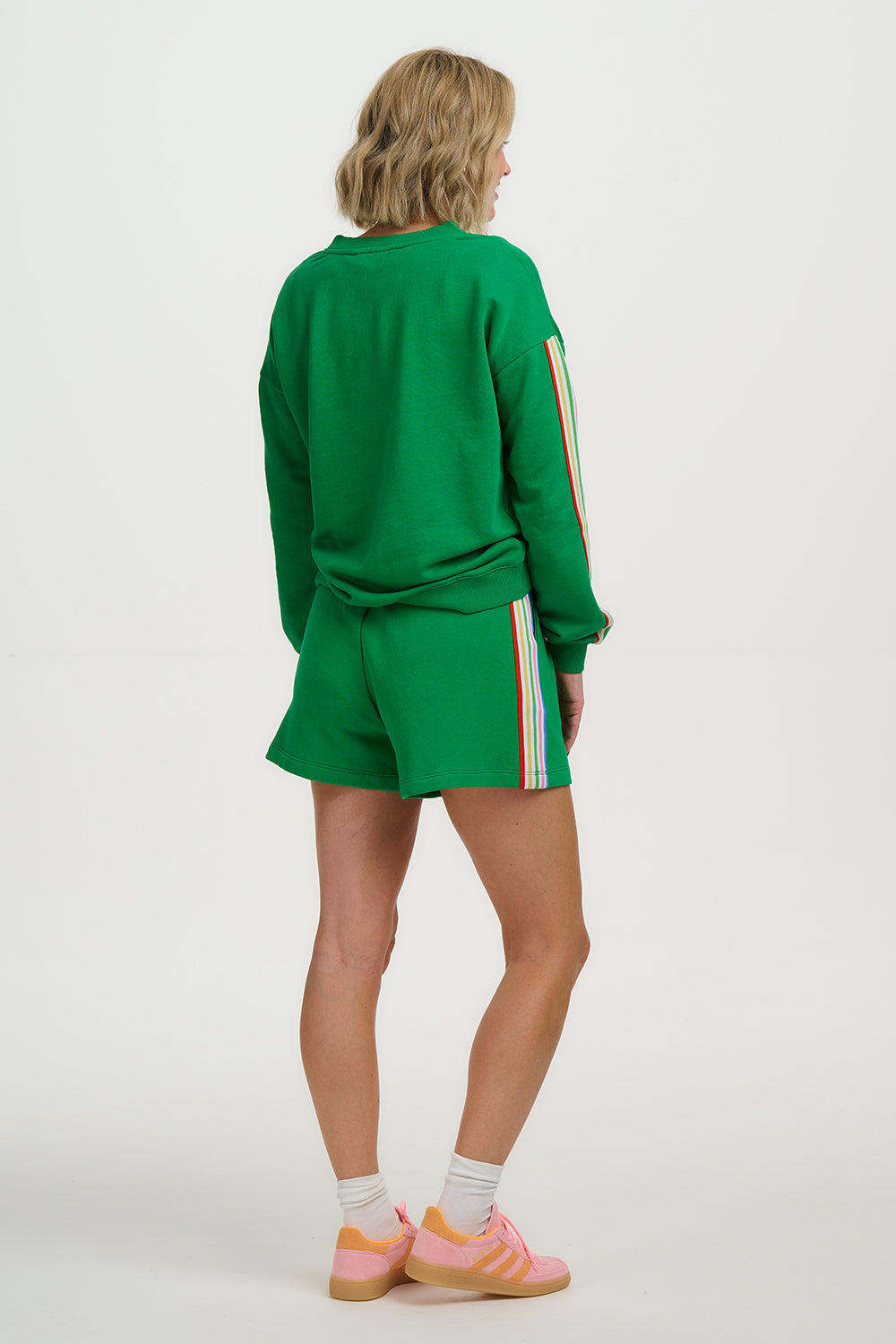 Person wearing a green tracksuit with colorful stripes on a white background