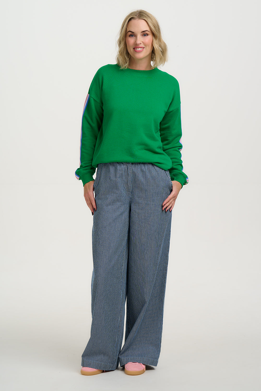 Woman wearing a green sweater and blue pants on a white background