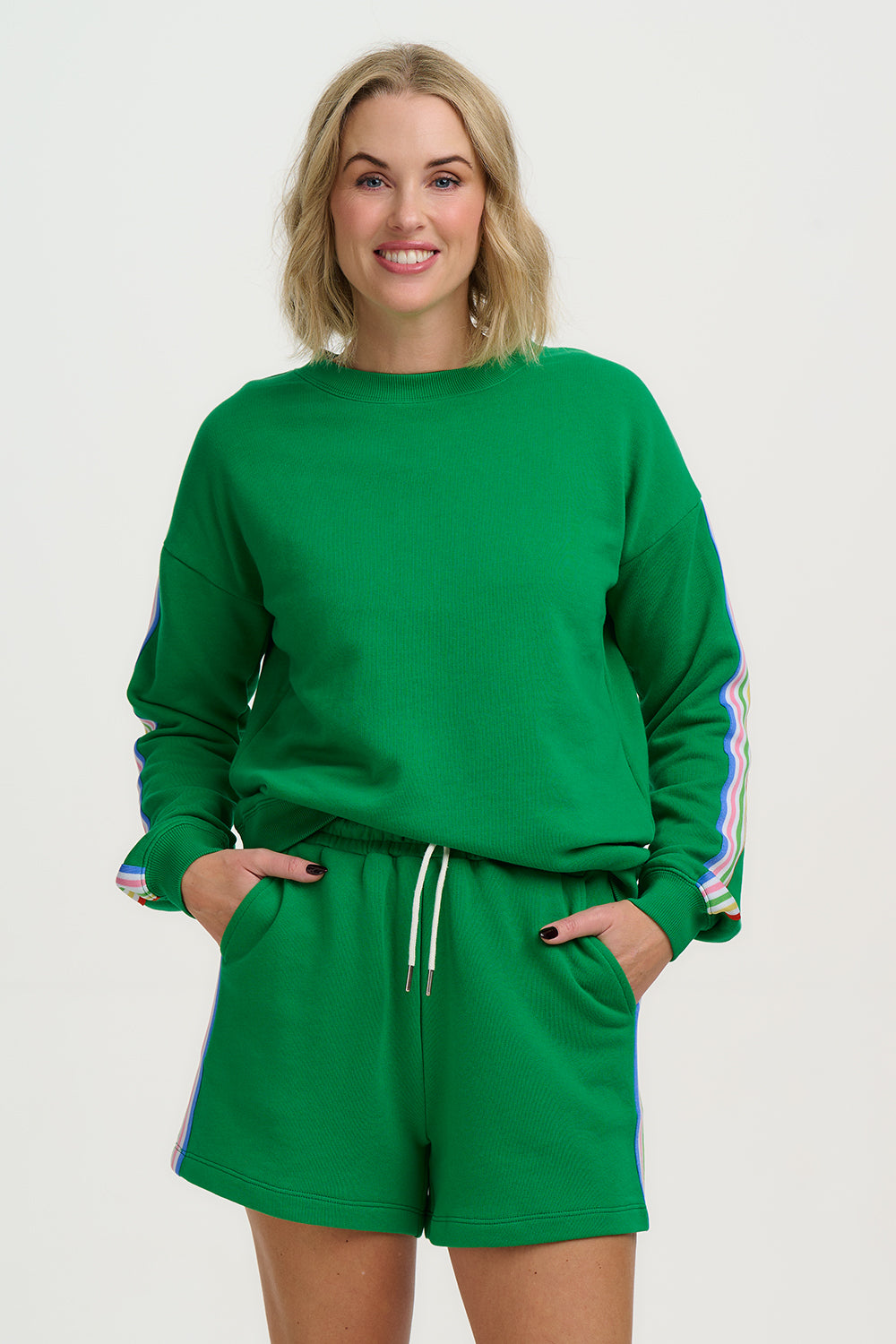 Woman wearing a green sweatshirt and shorts set with colorful sleeves on a white background