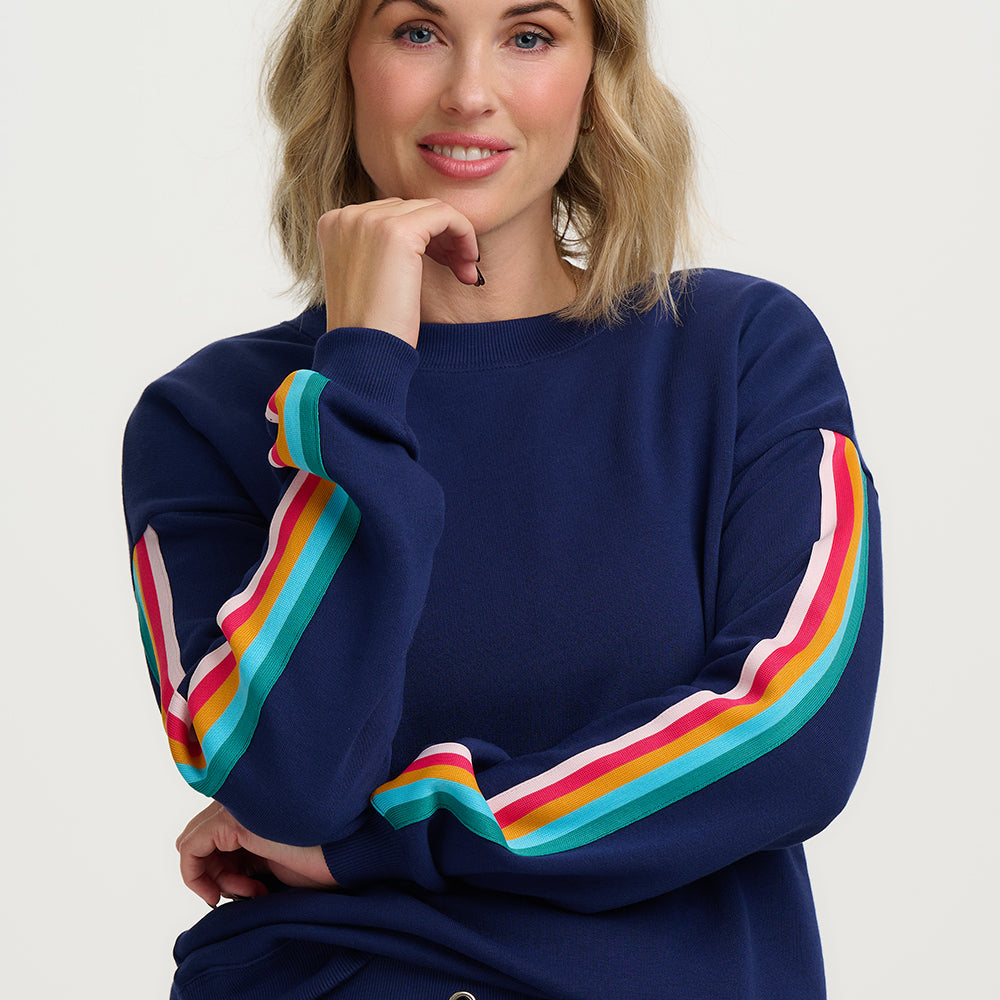 Woman wearing a navy sweater with colorful sleeves against a white background