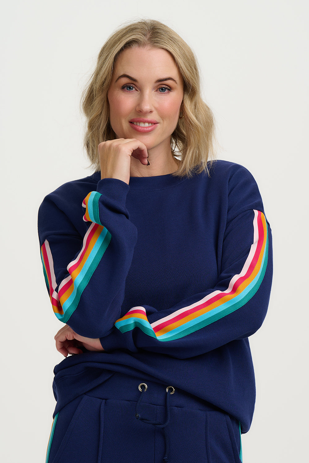 Woman wearing a navy sweater with colorful sleeves against a white background