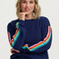 Woman wearing a navy sweater with colorful sleeves against a white background