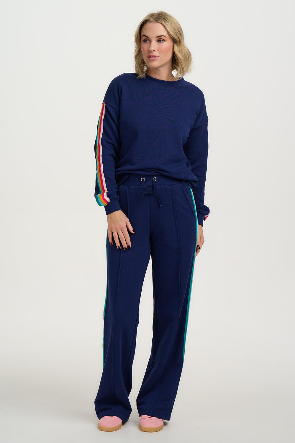 Woman wearing a navy tracksuit with colorful stripes on a white background