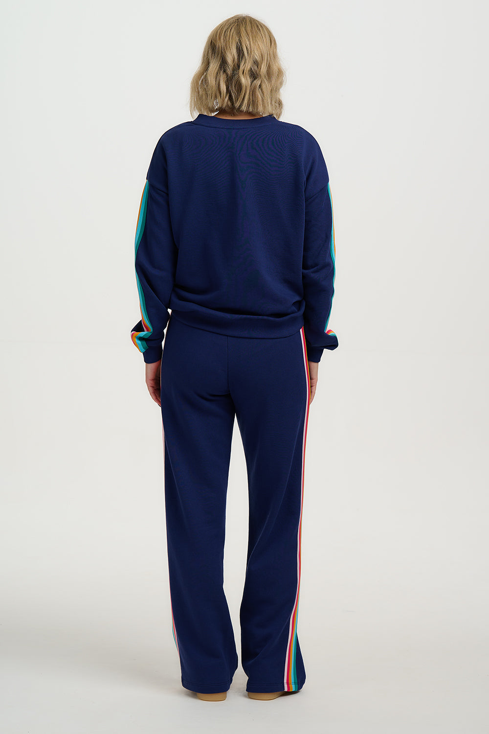 Person wearing a navy tracksuit with colorful stripes on a white background