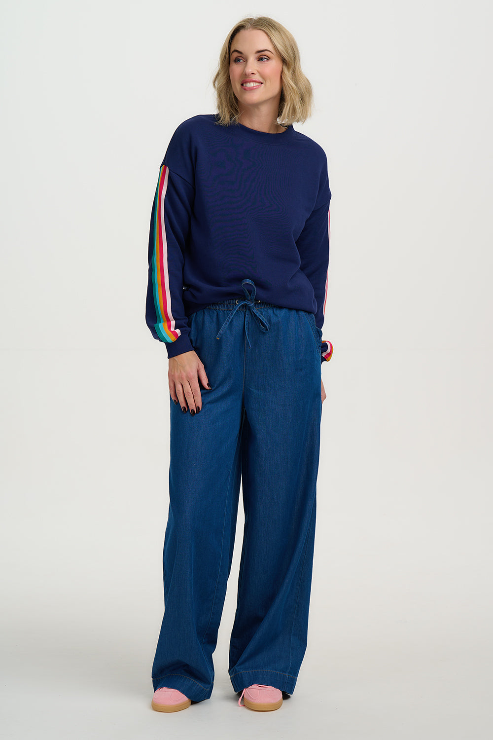 Woman wearing a navy blue outfit with colorful stripes on a white background