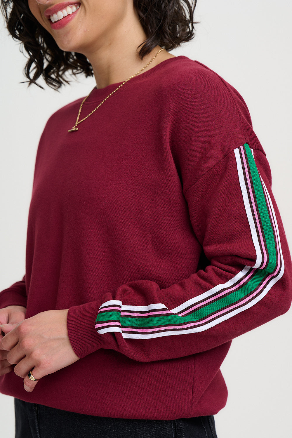 Maroon sweatshirt with green and white stripes on sleeves worn by a person