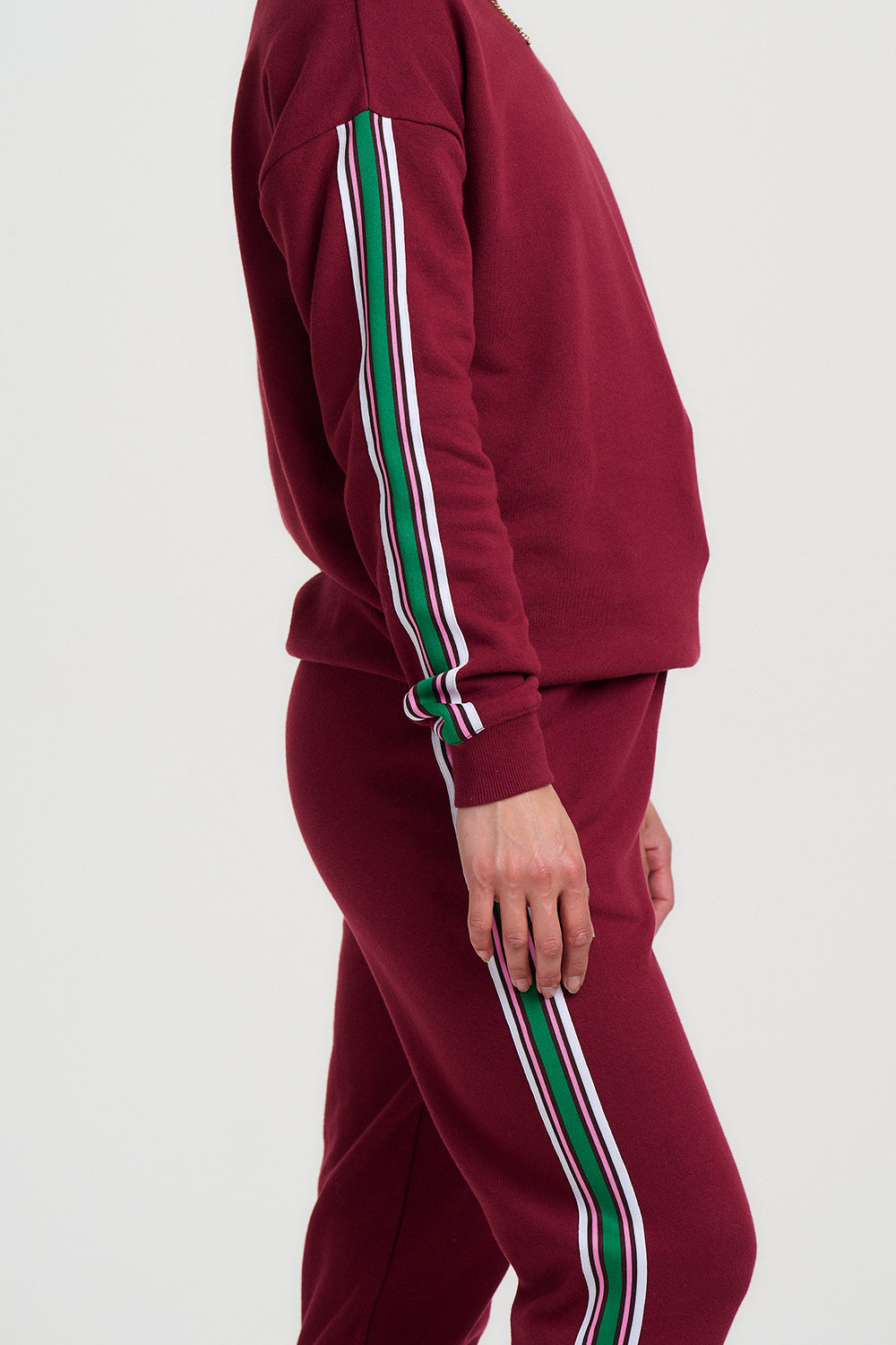 Maroon tracksuit with green and white stripes on a light gray background