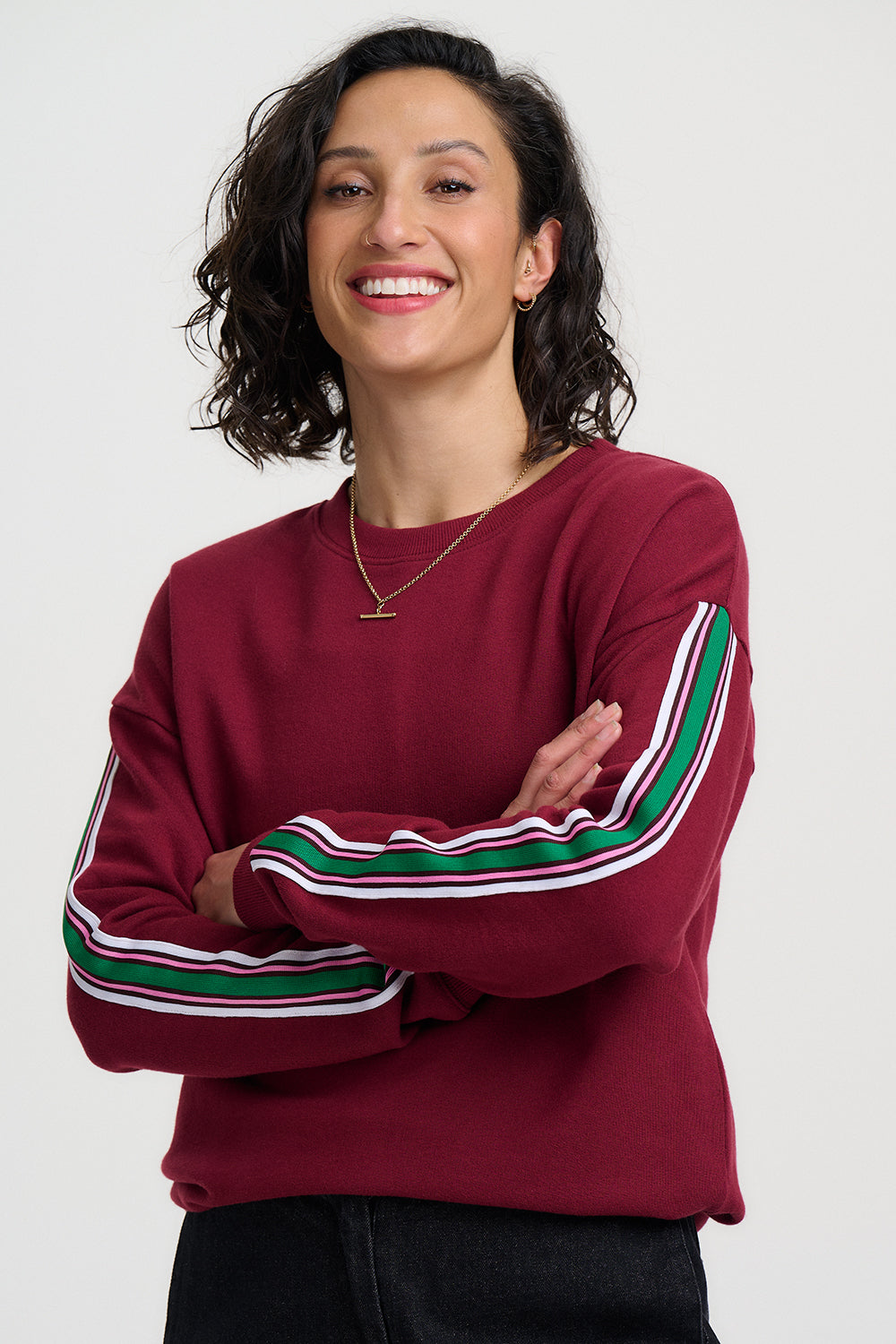 Woman wearing a burgundy sweater with colorful stripes on a white background
