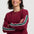Woman wearing a burgundy sweater with colorful stripes on a white background