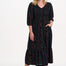 Sugarhill Brighton model wearing a black dress with colourful patterns on a white background
