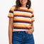 Sugarhill Brighton model wearing a colourful striped shirt and blue jeans on a white background