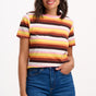 Sugarhill Brighton model wearing a colourful striped shirt and blue jeans on a white background