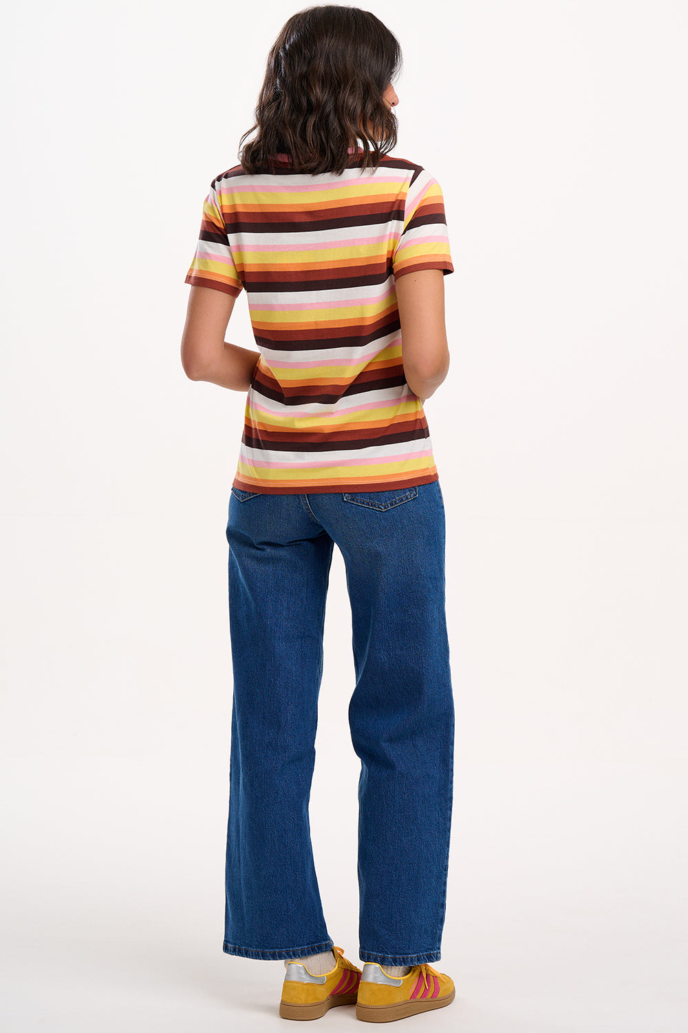 Sugarhill Brighton model wearing a striped shirt and blue jeans on a white background