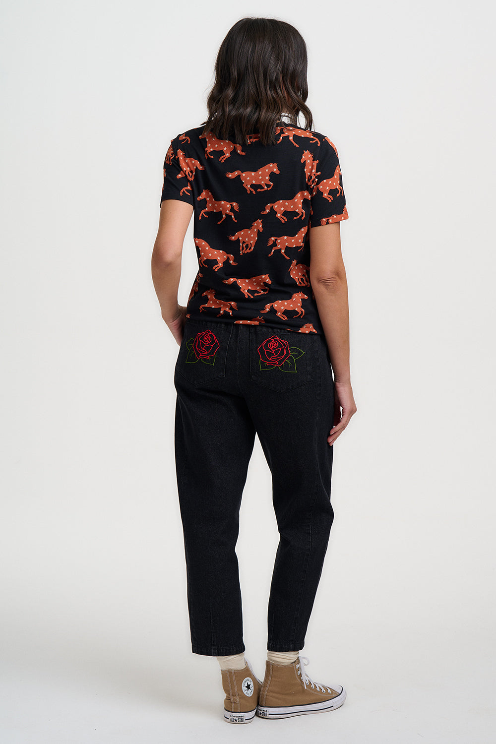 Person wearing a black t-shirt with orange animal prints and black pants on a white background