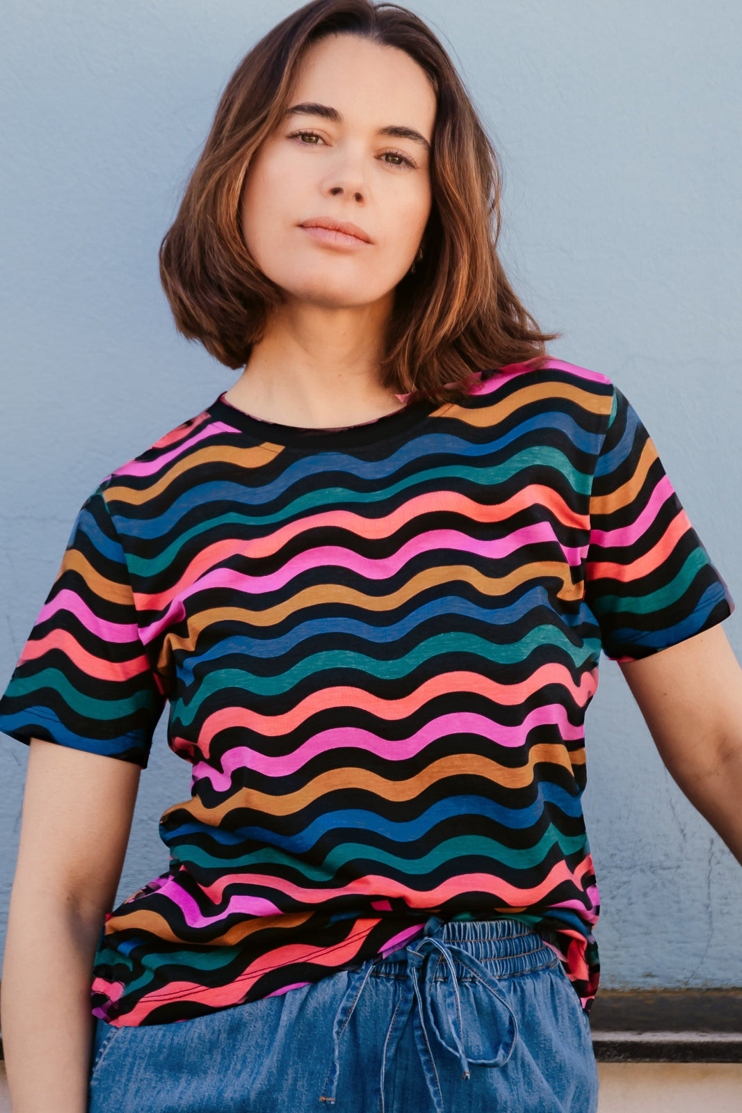 A woman modeling a black and multicolored wavy chevron stripe t-shirt.