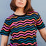 A woman modeling a black and multicolored wavy chevron stripe t-shirt.