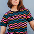 A woman modeling a black and multicolored wavy chevron stripe t-shirt.