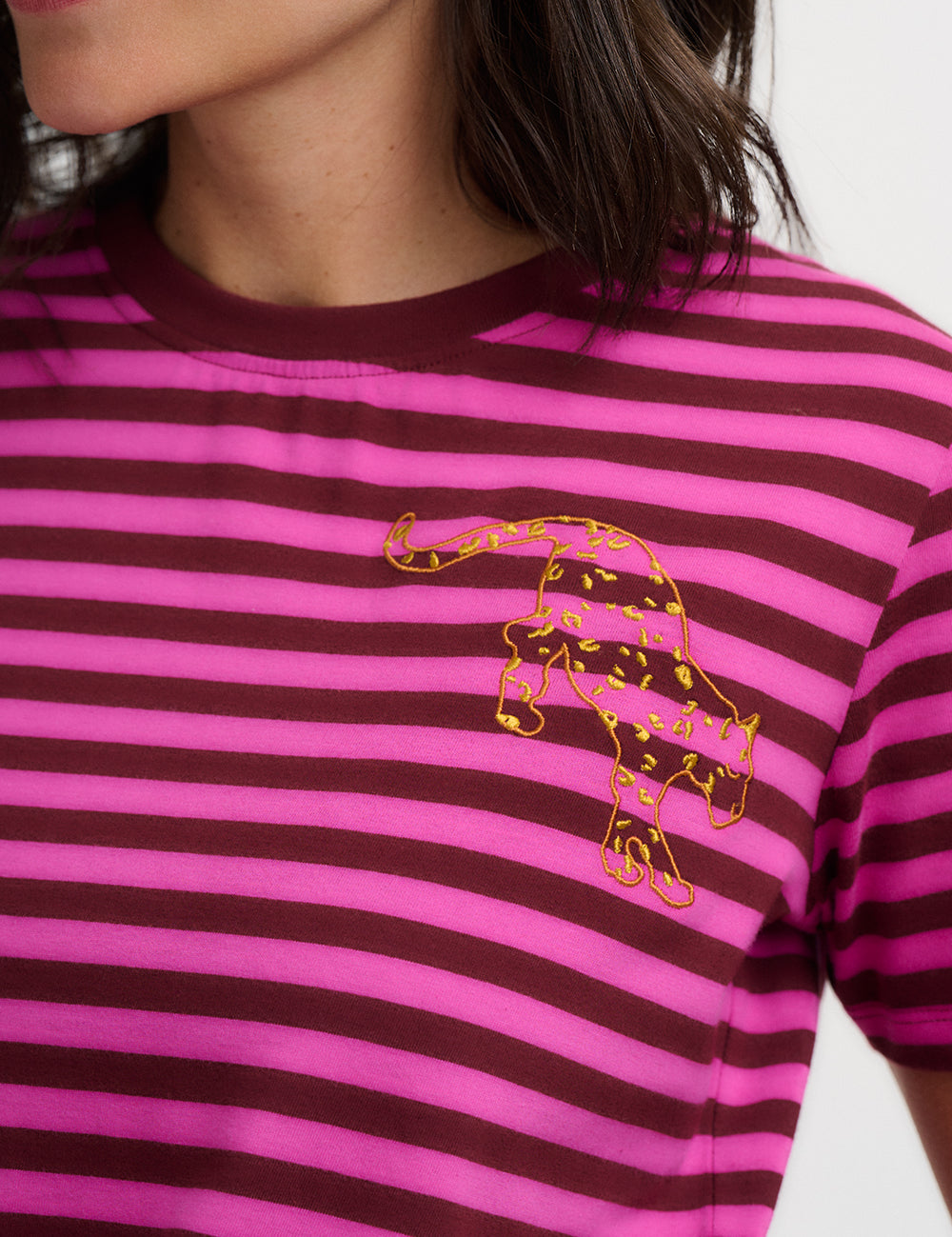 Person wearing a pink and brown striped shirt with a gold panther design.