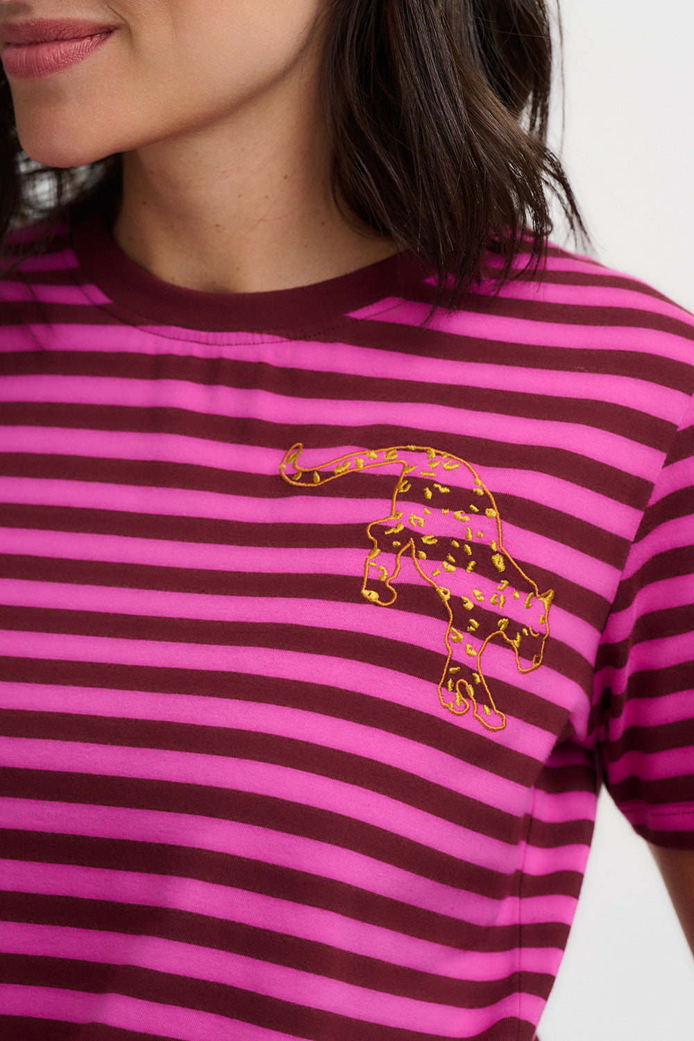 Person wearing a pink and brown striped shirt with a gold panther design.