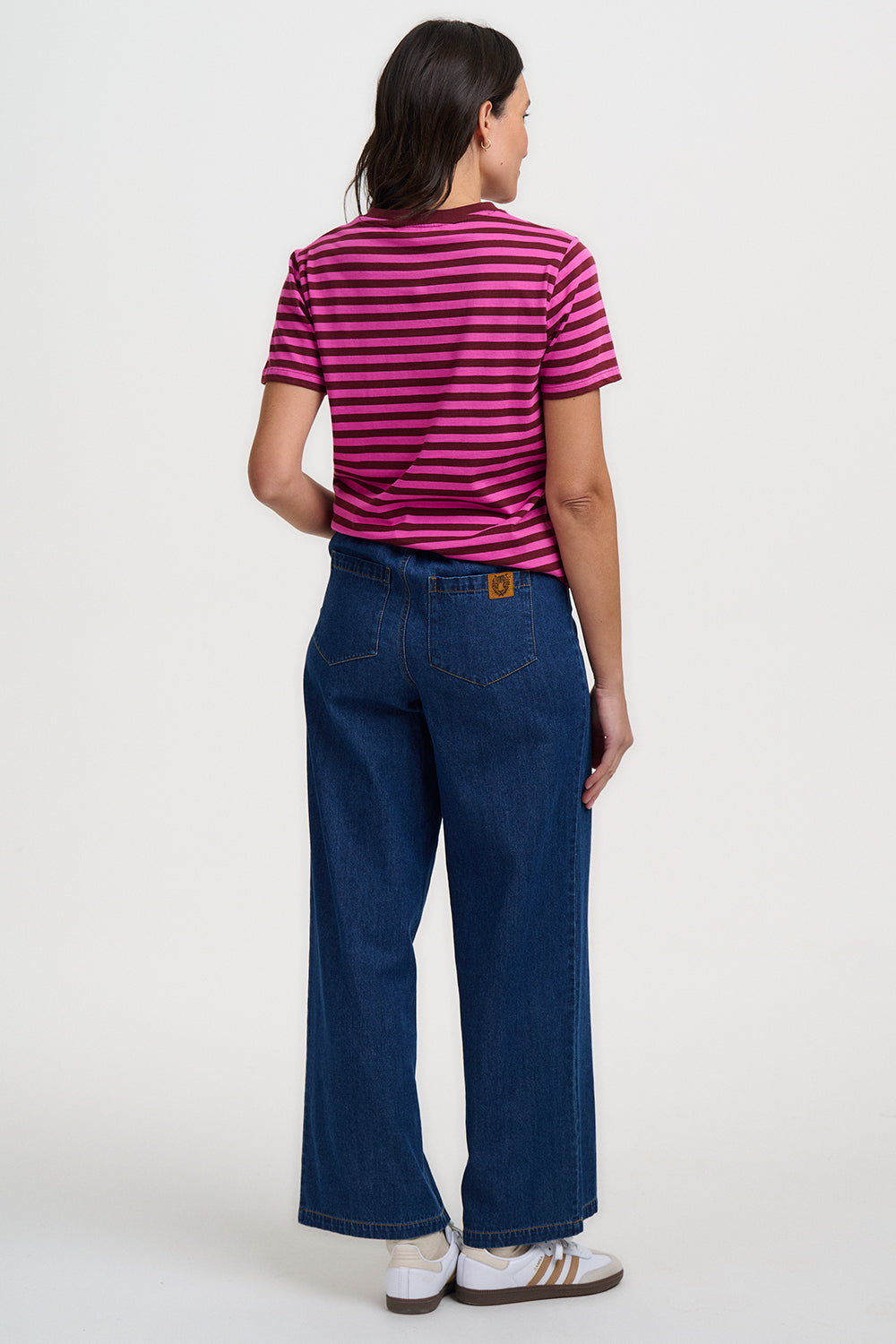 Person wearing a striped shirt and blue jeans on a white background