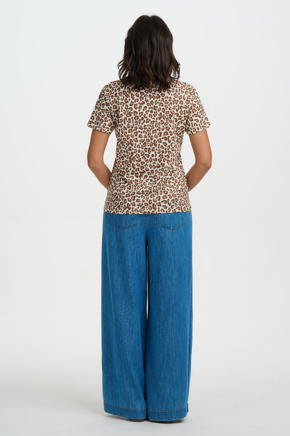 Person wearing a leopard print top and blue jeans on a white background