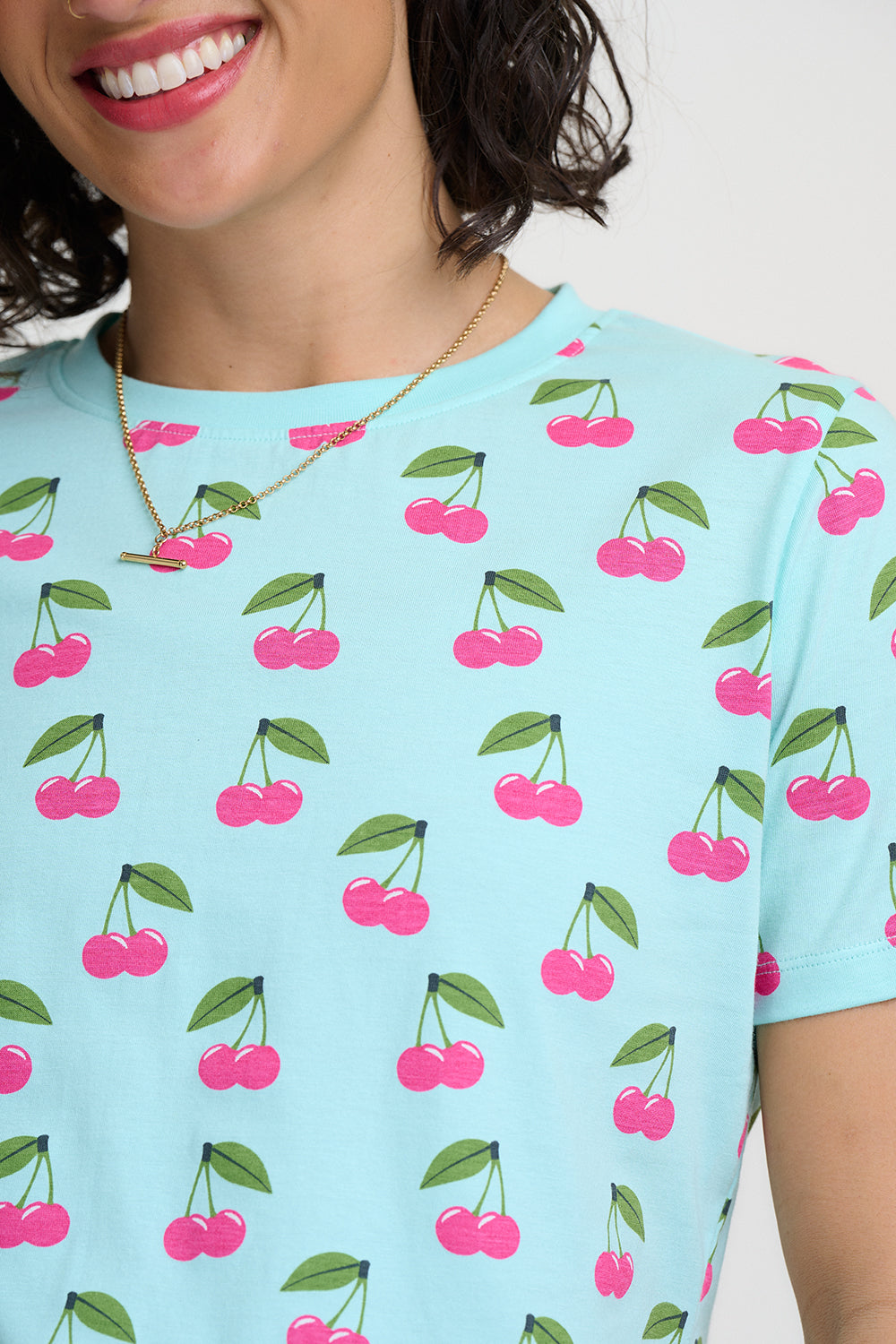 Light blue t-shirt with pink cherry pattern on a white background