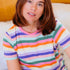Woman wearing a colorful striped shirt sitting on a couch.