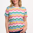 A woman smiling and wearing a multicolored wavy rainbow stripe t-shirt with a crew neck.