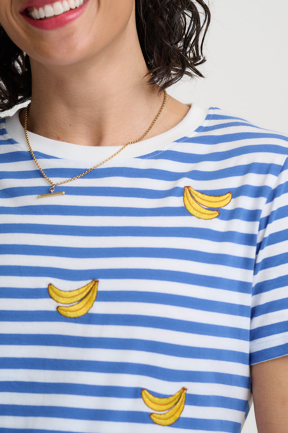 Blue and white striped t-shirt with yellow banana prints on a plain background